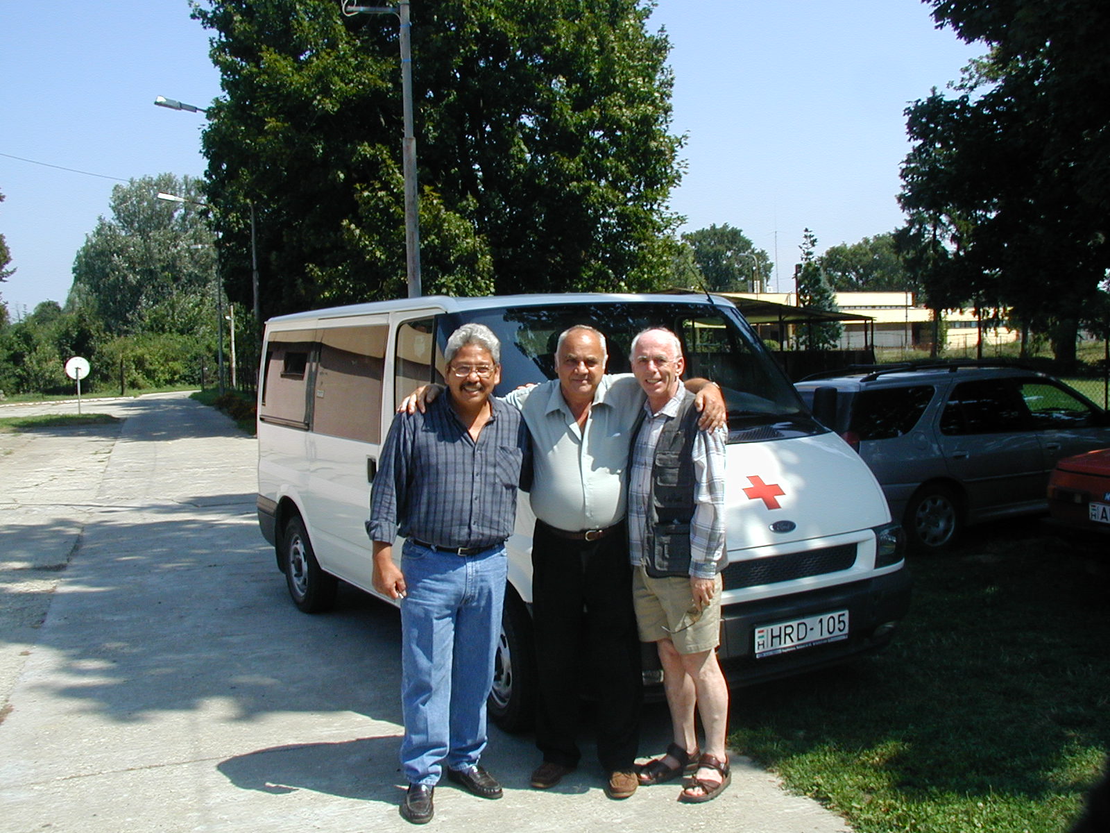 Frank Mendiola, Dr. Labady and Fr. John standing in front of the bus provided by Hands that Help.